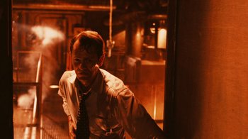Movie still from “Saw VI” (2009), directed by Kevin Greutert – A man wearing a suit and tie standing in front of a door; Medium shot, Low angle
