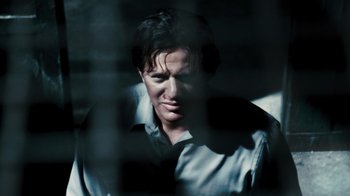 Movie still from “Saw VI” (2009), directed by Kevin Greutert – A man in a gray shirt is looking through a window; Close Up shot, Low angle