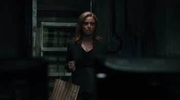 Movie still from “Saw VI” (2009), directed by Kevin Greutert – A woman in a black jacket holding a brown bag; Medium shot, Over the shoulder angle