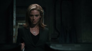 Movie still from “Saw VI” (2009), directed by Kevin Greutert – A woman in a black jacket is standing in a dark room; Close Up shot, Over the shoulder angle