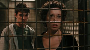 Movie still from “Saw VI” (2009), directed by Kevin Greutert – A woman and a man behind a metal fence; Close Up shot, Over the shoulder angle