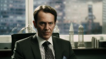 Movie still from “Saw VI” (2009), directed by Kevin Greutert – A man wearing a suit and tie sitting in front of a window; Close Up shot, Over the shoulder angle