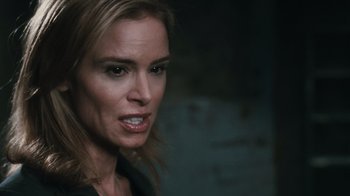 Movie still from “Saw VI” (2009), directed by Kevin Greutert – A woman's face in a dimly - lit room; Close Up shot, Over the shoulder angle