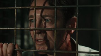 Movie still from “Saw VI” (2009), directed by Kevin Greutert – A person behind a fence; Close Up shot, Over the shoulder angle