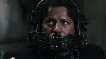 Movie still from “Saw VI” (2009), directed by Kevin Greutert – A man with a helmet on his face; Close Up shot, Over the shoulder angle