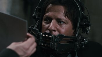 Movie still from “Saw VI” (2009), directed by Kevin Greutert – A man with a helmet on his face and a cell phone; Close Up shot, Over the shoulder angle