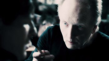 Movie still from “Saw VI” (2009), directed by Kevin Greutert – An old woman with white hair is smoking a cigarette; Close Up shot, Over the shoulder angle