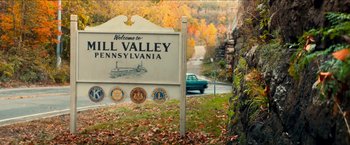 Movie still from “Scary Stories to Tell in the Dark” (2019), directed by André Øvredal – A welcome sign in the middle of a forest; Extreme Wide shot, High angle