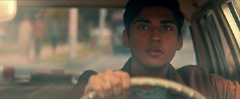 Movie still from “Scary Stories to Tell in the Dark” (2019), directed by André Øvredal – A young man driving a car in the street; Close Up shot, Over the shoulder angle