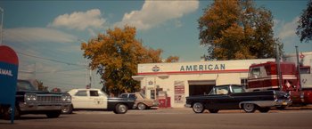 Movie still from “Scary Stories to Tell in the Dark” (2019), directed by André Øvredal – An old time gas station with cars parked on the side of the road; Extreme Wide shot, Low angle