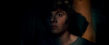 Movie still from “Scary Stories to Tell in the Dark” (2019), directed by André Øvredal – A young man with curly hair stares into the camera; Close Up shot, Low angle