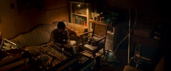 Movie still from “Scary Stories to Tell in the Dark” (2019), directed by André Øvredal – A man sitting on a couch in a living room; Wide shot, High angle