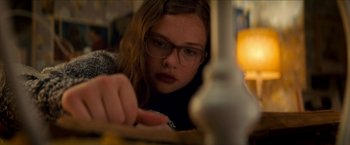 Movie still from “Scary Stories to Tell in the Dark” (2019), directed by André Øvredal – A young girl wearing glasses is writing at a table; Close Up shot, High angle