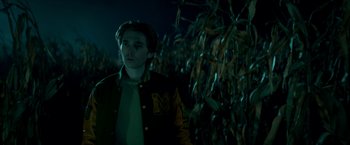 Movie still from “Scary Stories to Tell in the Dark” (2019), directed by André Øvredal – A man standing in front of a corn field at night; Medium shot, Over the shoulder angle