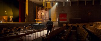 Movie still from “Scary Stories to Tell in the Dark” (2019), directed by André Øvredal – A man standing in front of a stage in a theater; Extreme Wide shot, Low angle