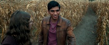 Movie still from “Scary Stories to Tell in the Dark” (2019), directed by André Øvredal – A man in a leather jacket standing next to a field; Medium shot, Over the shoulder angle