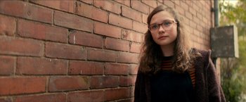 Movie still from “Scary Stories to Tell in the Dark” (2019), directed by André Øvredal – A woman with glasses standing in front of a brick wall; Close Up shot, Low angle