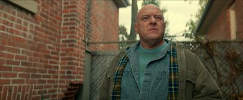 Movie still from “Scary Stories to Tell in the Dark” (2019), directed by André Øvredal – A bald man wearing a blue shirt and a plaid shirt; Medium shot, Low angle