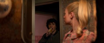 Movie still from “Scary Stories to Tell in the Dark” (2019), directed by André Øvredal – A young man eating a banana in front of a mirror; Medium shot, Over the shoulder angle