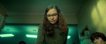 Movie still from “Scary Stories to Tell in the Dark” (2019), directed by André Øvredal – A woman with long hair wearing glasses and a sweater; Medium shot, Low angle