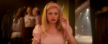 Movie still from “Scary Stories to Tell in the Dark” (2019), directed by André Øvredal – A woman in a pink and white striped dress with red lipstick; Close Up shot, Low angle