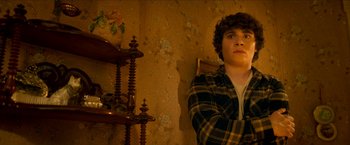 Movie still from “Scary Stories to Tell in the Dark” (2019), directed by André Øvredal – A young man leaning against a wall with his arms crossed; Medium shot, Low angle