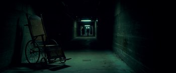 Movie still from “Scary Stories to Tell in the Dark” (2019), directed by André Øvredal – A person is walking down a dark hallway with a cart; Wide shot, Low angle