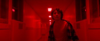 Movie still from “Scary Stories to Tell in the Dark” (2019), directed by André Øvredal – A man standing in a hallway with red lighting; Medium shot, Low angle