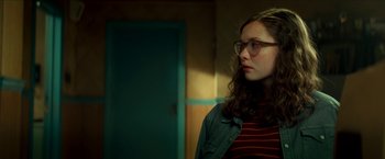 Movie still from “Scary Stories to Tell in the Dark” (2019), directed by André Øvredal – A woman wearing glasses and a jean jacket looking to her left; Close Up shot, Over the shoulder angle