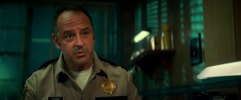 Movie still from “Scary Stories to Tell in the Dark” (2019), directed by André Øvredal – A man in a police uniform is looking at the camera; Close Up shot, Over the shoulder angle