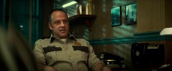 Movie still from “Scary Stories to Tell in the Dark” (2019), directed by André Øvredal – A man sitting in a chair in a room; Medium shot, Low angle