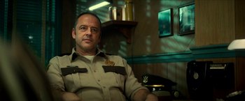 Movie still from “Scary Stories to Tell in the Dark” (2019), directed by André Øvredal – A man sitting in a chair wearing a uniform; Close Up shot, Low angle