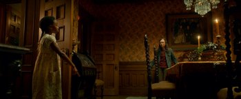 Movie still from “Scary Stories to Tell in the Dark” (2019), directed by André Øvredal – A woman standing next to a chair in a living room; Wide shot, High angle