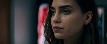 Movie still from “Scream” (2022), directed by Matt Bettinelli-Olpin – A woman's face with long brown hair; Close Up shot, Over the shoulder angle