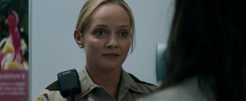 Movie still from “Scream” (2022), directed by Matt Bettinelli-Olpin – A woman in a police uniform looking at the camera; Close Up shot, Over the shoulder angle