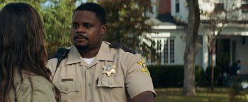 Movie still from “Scream” (2022), directed by Matt Bettinelli-Olpin – A man in a uniform is standing in front of a house; Close Up shot, Over the shoulder angle