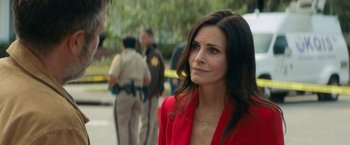 Movie still from “Scream” (2022), directed by Matt Bettinelli-Olpin – A woman in a red jacket standing next to a police car; Close Up shot, Over the shoulder angle
