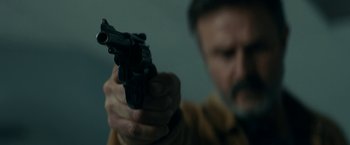 Movie still from “Scream” (2022), directed by Matt Bettinelli-Olpin – A man holding a gun in his right hand; Close Up shot, Low angle