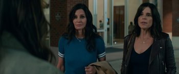 Movie still from “Scream” (2022), directed by Matt Bettinelli-Olpin – Courteney cox in a scene from the tv series cougar town; Medium shot, Over the shoulder angle