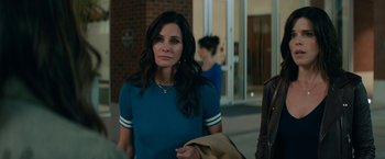 Movie still from “Scream” (2022), directed by Matt Bettinelli-Olpin – A woman in a blue shirt is standing outside; Medium shot, Over the shoulder angle