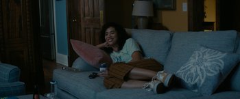 Movie still from “Scream” (2022), directed by Matt Bettinelli-Olpin – A woman sitting on top of a couch holding a drink; Medium shot, High angle
