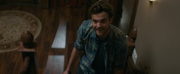 Movie still from “Scream” (2022), directed by Matt Bettinelli-Olpin – A man in a plaid shirt smiling for the camera; Medium shot, Overhead angle