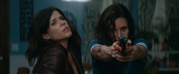 Movie still from “Scream” (2022), directed by Matt Bettinelli-Olpin – Two women are holding guns in a room; Medium shot, Low angle