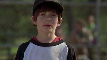 Movie still from “Searching for Bobby Fischer” (1993), directed by Steven Zaillian – A young boy wearing a baseball uniform and hat; Close Up shot, Over the shoulder angle