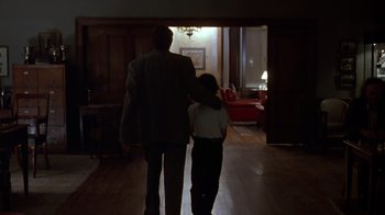 Movie still from “Searching for Bobby Fischer” (1993), directed by Steven Zaillian – A man and a woman are walking in a dark room; Wide shot, Over the shoulder angle