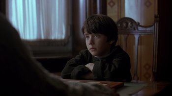 Movie still from “Searching for Bobby Fischer” (1993), directed by Steven Zaillian – A boy sitting at a table with his arms crossed; Close Up shot, Over the shoulder angle