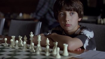 Movie still from “Searching for Bobby Fischer” (1993), directed by Steven Zaillian – A boy sitting in front of a chessboard with his arms crossed; Close Up shot, Over the shoulder angle