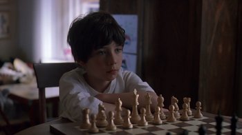 Movie still from “Searching for Bobby Fischer” (1993), directed by Steven Zaillian – A boy sitting in front of a chessboard with his arms crossed; Close Up shot, High angle