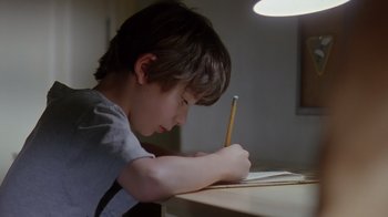 Movie still from “Searching for Bobby Fischer” (1993), directed by Steven Zaillian – A young boy is writing at a desk; Close Up shot, Over the shoulder angle