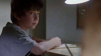 Movie still from “Searching for Bobby Fischer” (1993), directed by Steven Zaillian – A boy sitting at a table writing on a piece of paper; Close Up shot, High angle